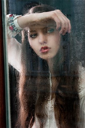 sad girls looking to window - Portrait of a lovely young lady looking through glass window - Indoor in a dark cloudy day, she looks down at right and her head is resting on the right arm Stock Photo - Budget Royalty-Free & Subscription, Code: 400-06087324