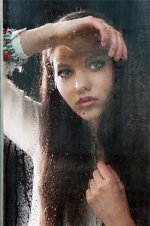 sad girls looking to window - Portrait of a lovely young lady looking through glass window - Indoor in a dark cloudy day, she looks in to the lens, her head is resting on the right arm and her left hand is near the chest Stock Photo - Budget Royalty-Free & Subscription, Code: 400-06087323