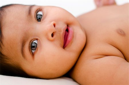 6 months old Indian baby girl smiling, lying on bed. Stock Photo - Budget Royalty-Free & Subscription, Code: 400-06098681
