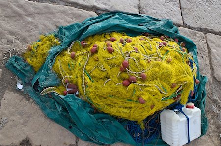 simsearch:6118-08910527,k - Yellow fishing nets pine, ropes and canister on stone paved ground Foto de stock - Super Valor sin royalties y Suscripción, Código: 400-06099889