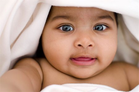 6 months old Indian baby girl smiling, lying on bed and covered by blanket Stock Photo - Budget Royalty-Free & Subscription, Code: 400-06092801