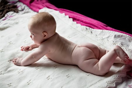 cute crying infant lies on his tummy with no diaper on a white rug Foto de stock - Super Valor sin royalties y Suscripción, Código: 400-06105096