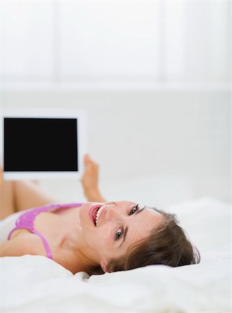Smiling girl laying in bed and using tablet PC Stock Photo - Budget Royalty-Free & Subscription, Code: 400-06106798