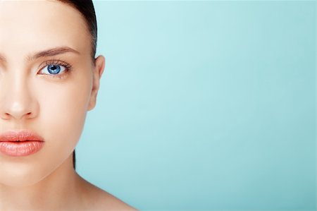 close-up half-face portrait of attractive young  caucasian  woman with pure skin over blue background Foto de stock - Super Valor sin royalties y Suscripción, Código: 400-06101133