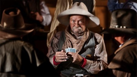 Bluffing card player in old American west saloon. Hands in focus. Stock Photo - Budget Royalty-Free & Subscription, Code: 400-06136082