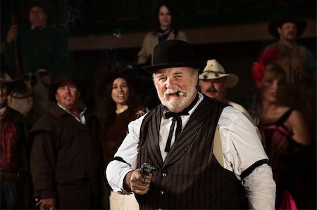 simsearch:400-06104096,k - Smiling old west bad guy with cigar and revolver Stock Photo - Budget Royalty-Free & Subscription, Code: 400-06136100