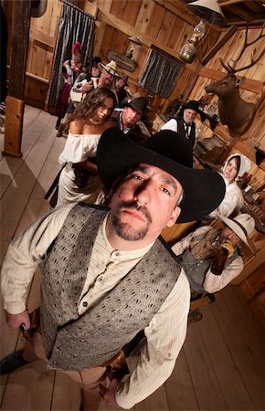 simsearch:400-06104096,k - Tough cowboy with hat in crowded old western saloon Stock Photo - Budget Royalty-Free & Subscription, Code: 400-06136525