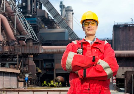 Factory worker posing in front of a blast furnace, wearing safety gear, including a hard hat, goggles and fire retardant coveralls Stock Photo - Budget Royalty-Free & Subscription, Code: 400-06137757