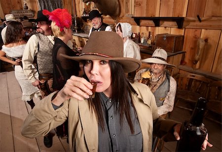 Cowgirl with bottle sipping whiskey from a shot glass Stock Photo - Budget Royalty-Free & Subscription, Code: 400-06138352