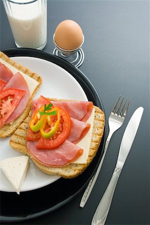 dairy eggs milk cheese - Pork tenderloin sandwiches, cheese, tomato and pepper arranged in ceramic plates in the company of soft-boiled egg placed in a special metal stand, fork, knife and glass of milk on neutral background. Stock Photo - Budget Royalty-Free & Subscription, Code: 400-06139268