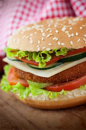 simsearch:400-06090558,k - Junk food concept. Deep fried chicken or fish burger sandwich with lettuce, tomato, cheese and cucumber on wooden background. Stock Photo - Budget Royalty-Free & Subscription, Code: 400-06174043