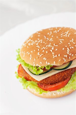 simsearch:400-06090558,k - Junk food concept. Deep fried chicken or fish burger sandwich with lettuce, tomato, cheese and cucumber on wooden background. Stock Photo - Budget Royalty-Free & Subscription, Code: 400-06176141