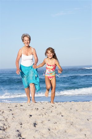 seven year old girl swimwear - Grandmother Running With Granddaughter Along Sandy Beach Stock Photo - Budget Royalty-Free & Subscription, Code: 400-06204457