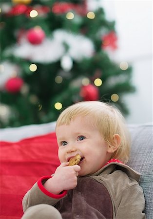 Happy baby eating cookie near Christmas tree Stock Photo - Budget Royalty-Free & Subscription, Code: 400-06208330