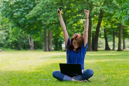 A beautiful brunette model working on a computer and talking on a mobile phone in an outdoor environment Stock Photo - Budget Royalty-Free & Subscription, Code: 400-06202817