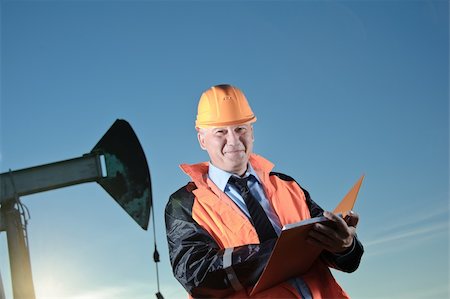 Oil worker in orange uniform and helmet on of background the pump jack and blue sky. Stock Photo - Budget Royalty-Free & Subscription, Code: 400-06395524
