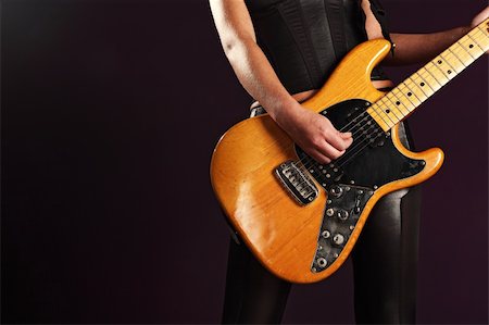 simsearch:400-04652753,k - Photo of the body of a female guitar player standing and playing over a dark background. Stock Photo - Budget Royalty-Free & Subscription, Code: 400-06418204