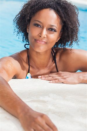 simsearch:400-06422339,k - A beautiful sexy young African American girl or young woman wearing a bikini and relaxing on the side of a swimming pool. Foto de stock - Super Valor sin royalties y Suscripción, Código: 400-06421516