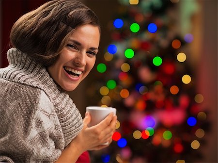 Happy young woman with cup of hot chocolate in front of Christmas tree Stock Photo - Budget Royalty-Free & Subscription, Code: 400-06463576