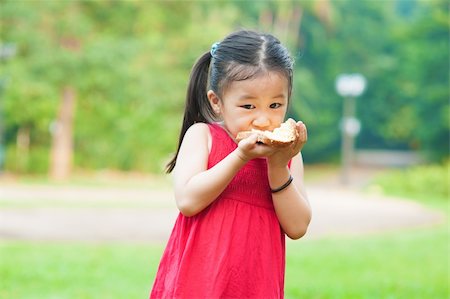 Little Asian girl eats a sandwich on fresh air Stock Photo - Budget Royalty-Free & Subscription, Code: 400-06479247