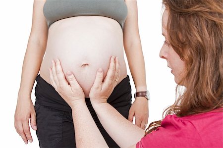 young midwife fingering at human belly. pregnant woman standing while midwife is sitting in front. horizontal picture isolated on white Stock Photo - Budget Royalty-Free & Subscription, Code: 400-06482347