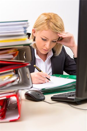 Confident blonde businesswoman filing documents in front of his computer, supporting his head with her left hand, surrounded by huge piles of documents. Stock Photo - Budget Royalty-Free & Subscription, Code: 400-06525357