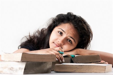 Tired and exhausted Young indian girl leaned over pile of  old books, isolated on white Stock Photo - Budget Royalty-Free & Subscription, Code: 400-06553966