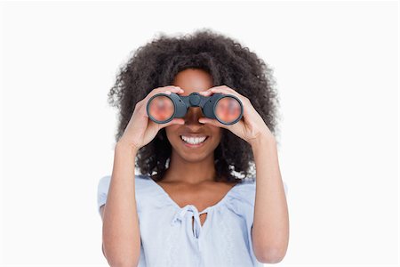 Young woman with curly hair looking through binoculars against a white background Stock Photo - Budget Royalty-Free & Subscription, Code: 400-06635122