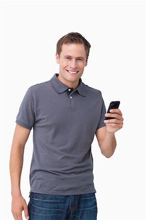 simsearch:400-06632132,k - Smiling young man holding his cellphone against a white background Stock Photo - Budget Royalty-Free & Subscription, Code: 400-06632138