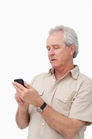 simsearch:400-06632132,k - Mature man typing text message on his cellphone against a white background Stock Photo - Budget Royalty-Free & Subscription, Code: 400-06632308