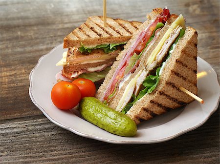 sumners (artist) - Photo of a club sandwich made with turkey, bacon, ham, tomato, cheese, lettuce, and garnished with a pickle and two cherry tomatoes. Stock Photo - Budget Royalty-Free & Subscription, Code: 400-06640218
