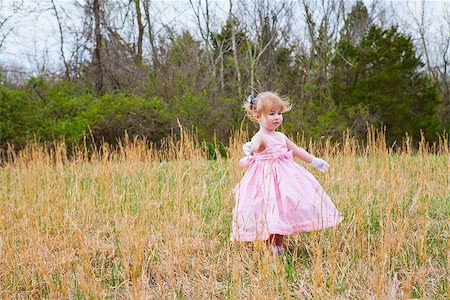A little girl in a pink dress and white gloves, dancing in a field of tall grass on a windy day. Stock Photo - Budget Royalty-Free & Subscription, Code: 400-06642855