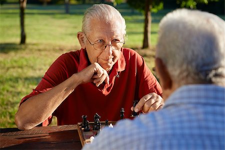 simsearch:400-06142278,k - Active retired people, old friends and free time, two senior men having fun and playing chess at park. Head and shoulders Stock Photo - Budget Royalty-Free & Subscription, Code: 400-06687491