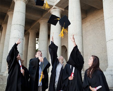 simsearch:400-06688304,k - Smiling graduates throwing their hats in the sky in front of their university Photographie de stock - Aubaine LD & Abonnement, Code: 400-06688301