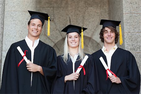 simsearch:400-06688304,k - Graduates holding their diploma while posing with university in backgroung Photographie de stock - Aubaine LD & Abonnement, Code: 400-06688389