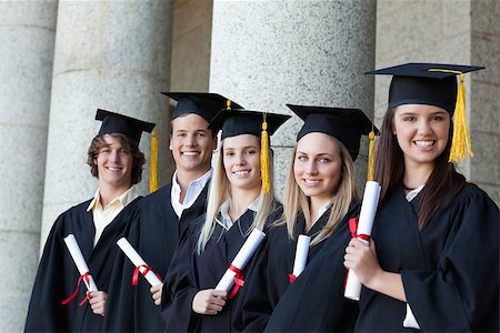 simsearch:400-06688304,k - Smiling graduates posing in single line with columns in background Photographie de stock - Aubaine LD & Abonnement, Code: 400-06688395