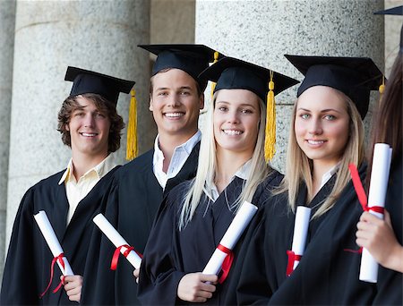 simsearch:400-06688304,k - Portrait of smiling graduates posing in single line with columns in background Photographie de stock - Aubaine LD & Abonnement, Code: 400-06688396