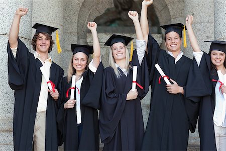 simsearch:400-06688304,k - Smiling graduates posing while raising arms in front of the university Photographie de stock - Aubaine LD & Abonnement, Code: 400-06688400