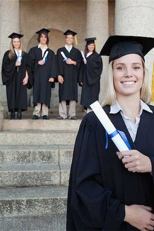 simsearch:400-06688304,k - Close-up of a blonde graduate smiling with her friends in background in front of the university Photographie de stock - Aubaine LD & Abonnement, Code: 400-06688424
