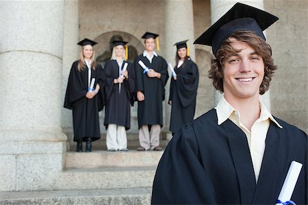 simsearch:400-06688304,k - Close-up of a smiling graduate smiling with her friends in background in front of the university Photographie de stock - Aubaine LD & Abonnement, Code: 400-06688425