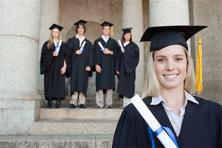 simsearch:400-06688304,k - Close-up of a blonde graduate with her friends in background in front of the university Photographie de stock - Aubaine LD & Abonnement, Code: 400-06688423