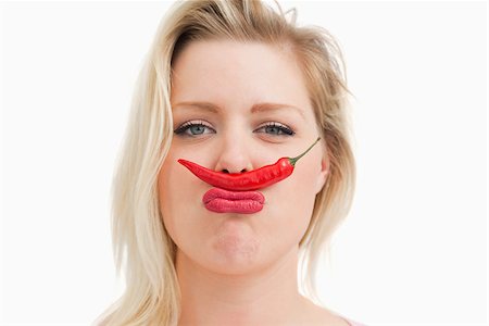 pimento - Blonde woman placing a chili between her nose and her mouth against a white background Stock Photo - Budget Royalty-Free & Subscription, Code: 400-06691101