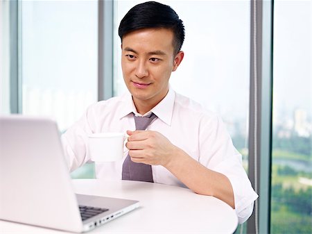 simsearch:614-06718128,k - young asian businessman looking at computer and drinking coffee in office. Stock Photo - Budget Royalty-Free & Subscription, Code: 400-06691800