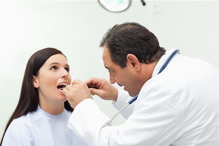 Doctor looking at the mouth of his patient in an examination room Stock Photo - Budget Royalty-Free & Subscription, Code: 400-06734164