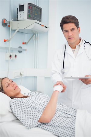 Doctor holding medical result and the hand of his patient in hospital ward Stock Photo - Budget Royalty-Free & Subscription, Code: 400-06734191