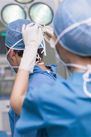 simsearch:400-06734297,k - Close up of a nurse tying a mask of a doctor in hospital ward Stock Photo - Budget Royalty-Free & Subscription, Code: 400-06734295