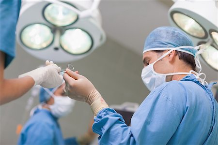 simsearch:400-06734297,k - Doctor receiving a surgical scissor from a nurse in operating theater Stock Photo - Budget Royalty-Free & Subscription, Code: 400-06734309