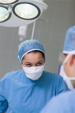 simsearch:400-06734297,k - Serious nurse looking at a doctor in operating theater Stock Photo - Budget Royalty-Free & Subscription, Code: 400-06734303