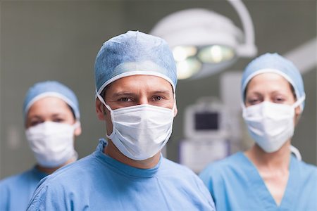 simsearch:400-06734297,k - Medical team looking at camera in operating theater Stock Photo - Budget Royalty-Free & Subscription, Code: 400-06734480