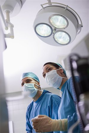 simsearch:400-06734297,k - Doctors next to surgical light in operating theater Stock Photo - Budget Royalty-Free & Subscription, Code: 400-06734515